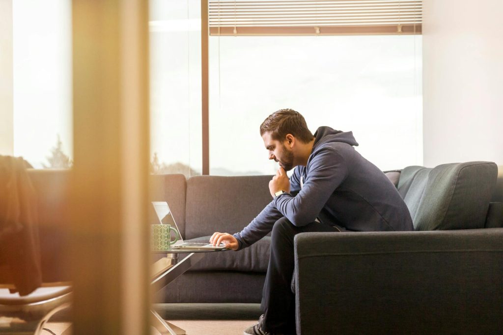 man using laptop sitting on couch