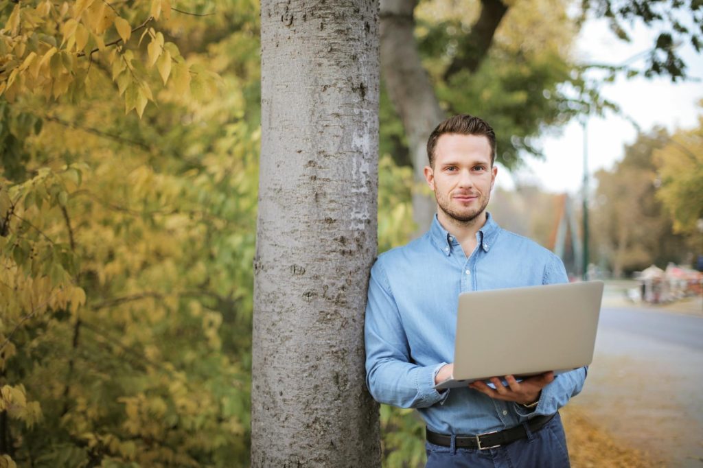 man in blue long sleeve holding a laptop computer